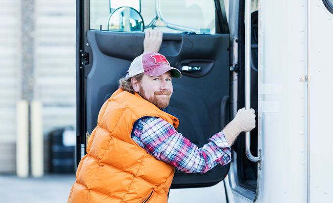 A fleet driver climbs into his semi truck.