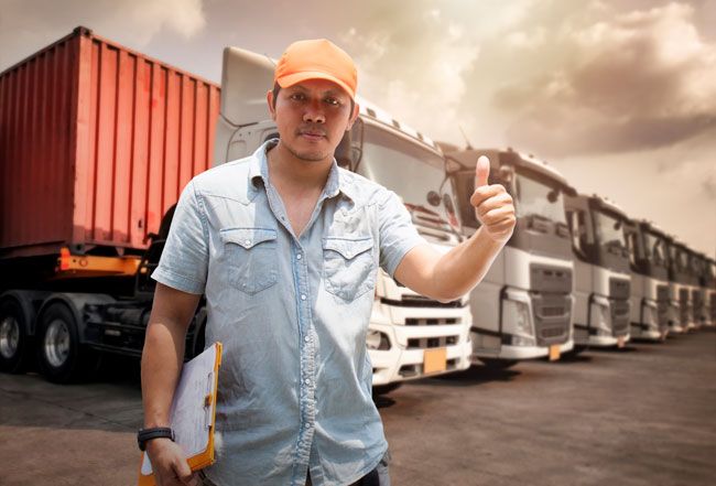 A happy maintenance guy gives a thumb’s up after checking a fleet of vehicles for safety.