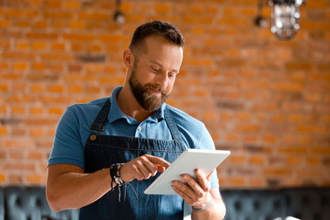 A business owner happily reviews the data on his tablet recording the fuel card usage of his fleet of vans.