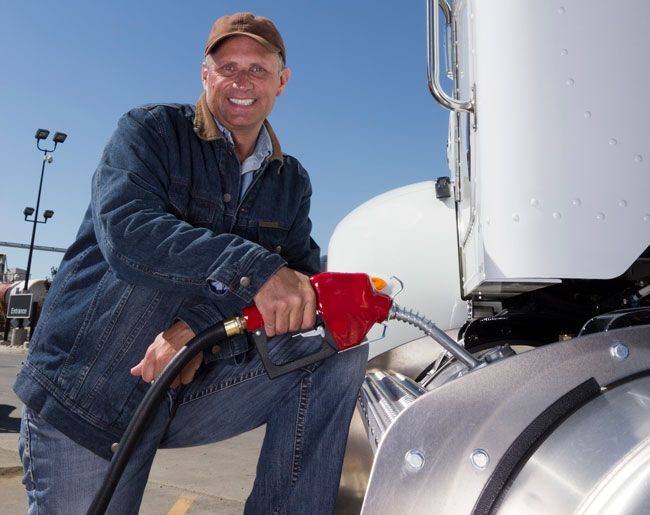A truck driver fuels his semi truck at a gas station using his fuel card.