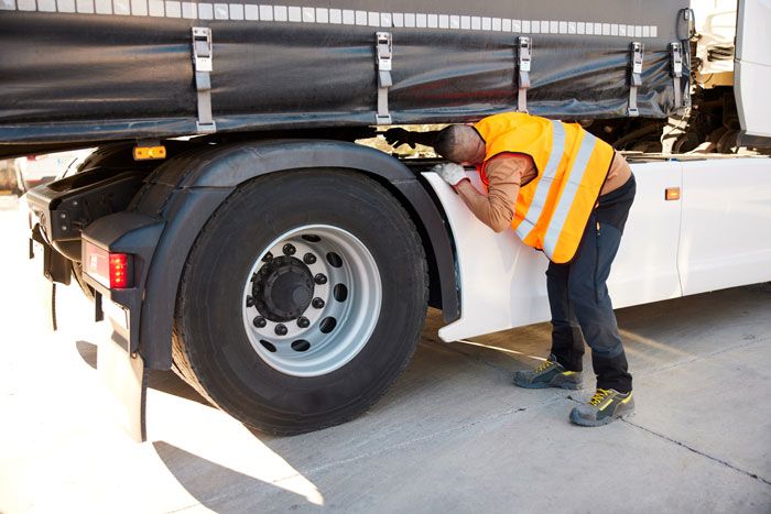A trucker inspects and reviews his semi truck.