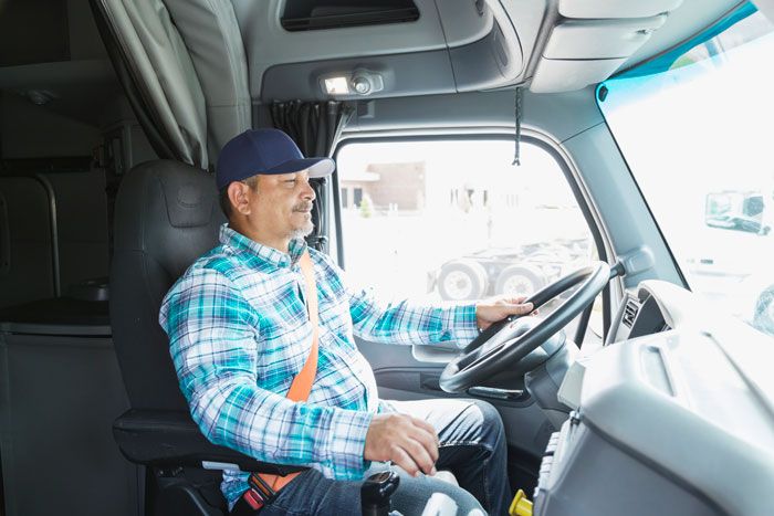 A truck driver in the cab of his fleet semi truck.