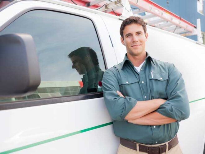 A business owner stands in front of his work van, satisfied with his fleet card.