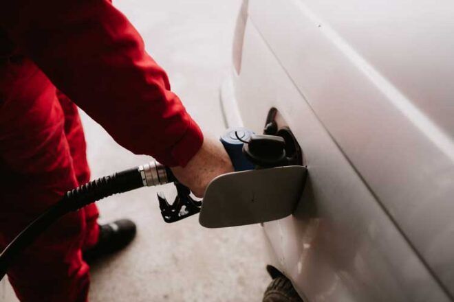 A fleet driver fueling his van at a gas station.